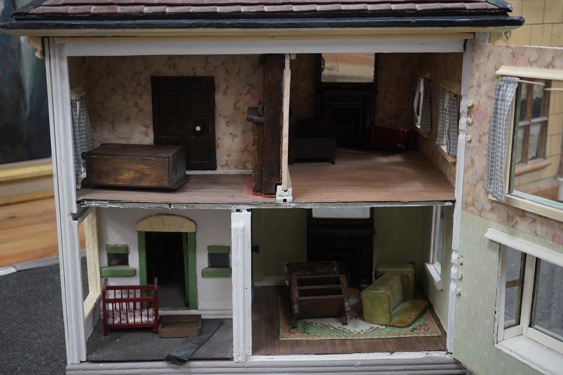 A mid-20th century green and white plywood doll's house, with a pyramid hip tiled roof, together with some plywood furniture including furniture from the Pit-A-Pat Series, height 67cm, width 54cm, depth 54cm. Condition -